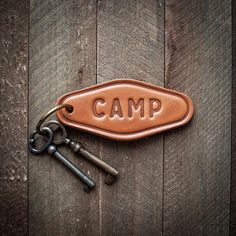 a leather keychain with the word camp on it and three keys attached to it