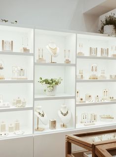 a room filled with lots of white shelves covered in vases and other items next to a wooden table