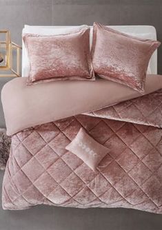 a bed with pink comforters and pillows on it