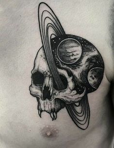 a man's chest with a skull and saturn tattoo on the top of it