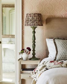 a bedroom with pink wallpaper and a lamp on the nightstand next to the bed