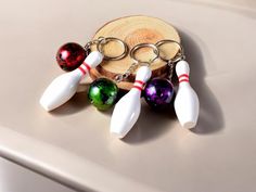 several key chains with bowling balls and pins on them sitting next to a piece of wood