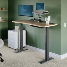 a computer desk with two monitors and a laptop on it in a green walled room