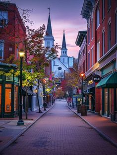 an empty street in the middle of a town with tall buildings and steeple spires