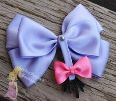 two small bows are sitting on top of a piece of wood, one is pink and the other is blue