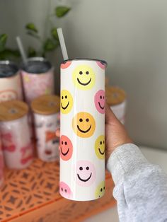 a person holding a cup with smiley faces on it and other cups in the background