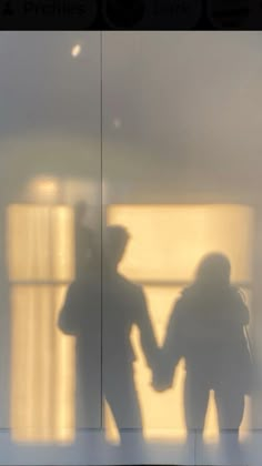 two people are holding hands in front of a glass wall with the reflection of them