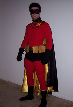 a man in a red and gold costume standing next to a white wall wearing a black mask