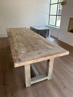 a large wooden table sitting on top of a hard wood floor next to a window