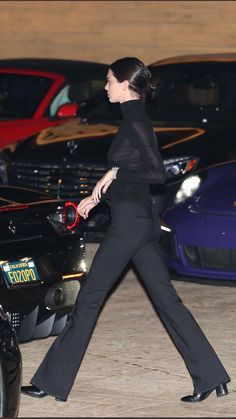 a woman walking in front of some parked cars