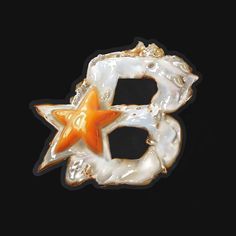 an orange and white brooch with a star on it's center, against a black background