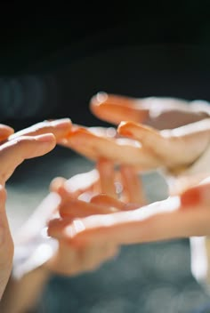 several hands reaching out towards each other with orange liquid on their fingertipss and one holding something in the other hand