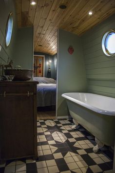 a bathroom with a tub, sink and toilet in it's corner next to a bed