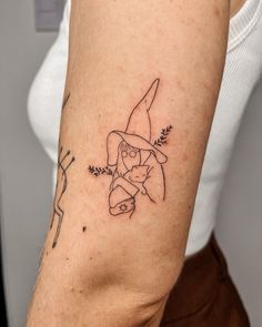 a woman with a tattoo on her arm holding a carrot and wearing a witches hat