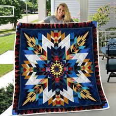 a woman is holding up a quilt on the porch