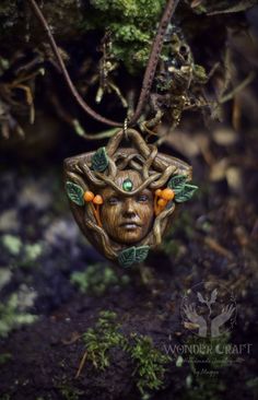 a green man's head hanging from a tree branch with leaves and oranges on it