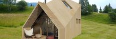 a small wooden house on top of a green field