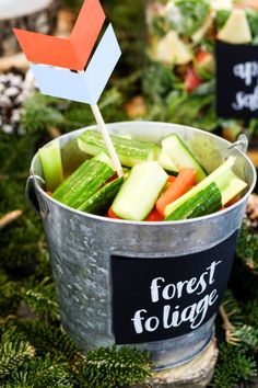 a bucket filled with cucumbers and carrots next to a sign that says forest foliage