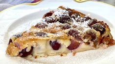 a piece of pie on a plate covered in powdered sugar and fruit toppings