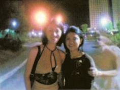 two women standing next to each other in front of a street with lights on it