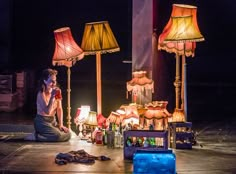 a man sitting on the ground in front of lamps