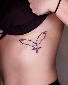 a woman's stomach with a bird tattoo on her side and the bottom part of her body