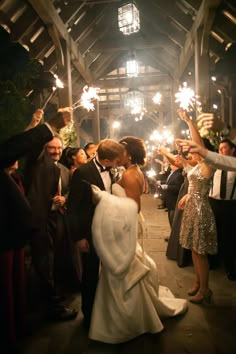 a newly married couple kissing in front of their guests with sparklers at the end