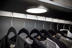 there is a light that is on above some clothes hanging from the rack in this room