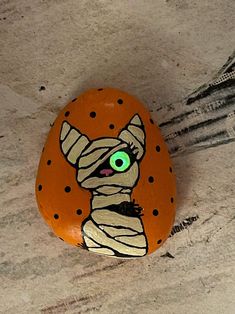 a painted rock with an image of a cat's head on it and green eyes