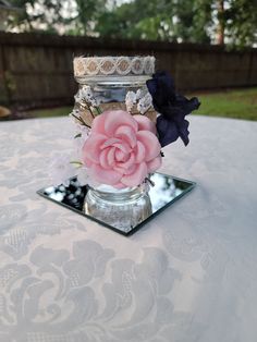 there is a vase with flowers in it on top of a glass tablecloth covered table