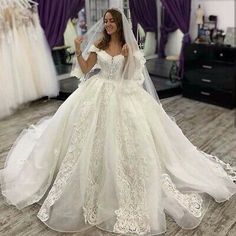 a woman wearing a wedding dress and veil standing in front of dresses on mannequins