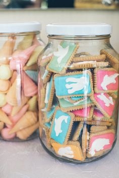 two jars filled with cookies and crackers on top of a table next to each other