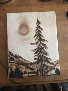 a wooden box with a painting on it sitting on a table next to some wires