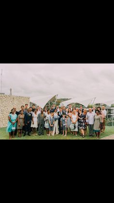 a group of people standing on top of a grass covered field next to each other