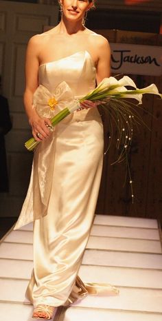 a woman is walking down the runway with flowers in her hand