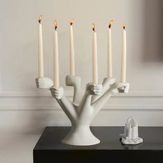 a group of white candles sitting on top of a table next to a figurine