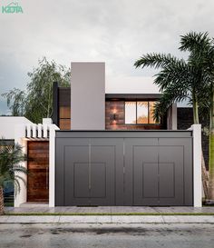 a modern house with two garages and palm trees