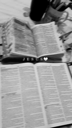 an open book with the word jesus on it sitting on a table next to other books