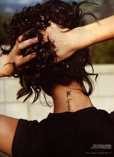 the back of a woman's head with her hands on her hair and writing