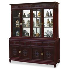 a wooden china cabinet with glass doors and carvings on the front, along with figurines