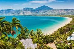 the beach is surrounded by palm trees and blue water, with mountains in the background