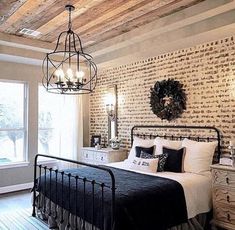 a bedroom with brick walls and wood floors, white bedding, chandelier