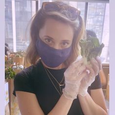 a woman wearing a face mask and holding broccoli