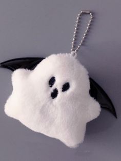 a white and black bat shaped keychain hanging from a chain