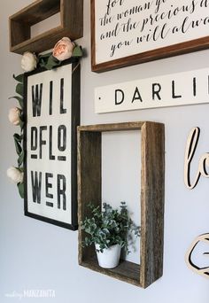 three wooden frames hanging on the wall with flowers in them