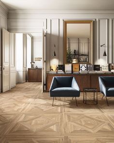 two blue chairs sitting next to each other on top of a hard wood floor in front of a mirror