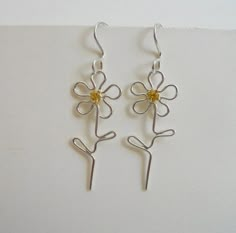 pair of silver and yellow flower earrings on white background