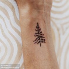 a small black pine tree tattoo on the wrist