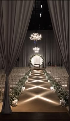 the aisle is decorated with white flowers and greenery for an elegant wedding ceremony at night