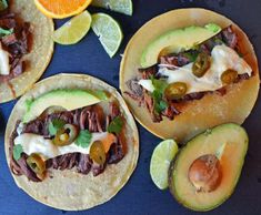 three tortillas topped with meat, cheese and veggies next to sliced oranges